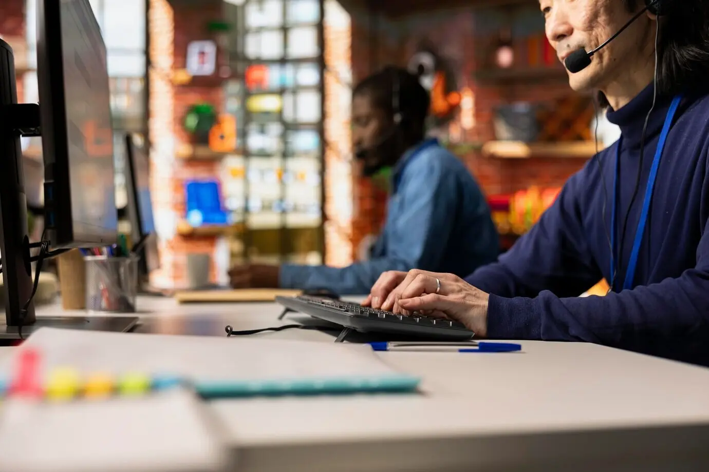 Оператор колл-центра говорит в микрофон гарнитуры и печатает на клавиатуре.